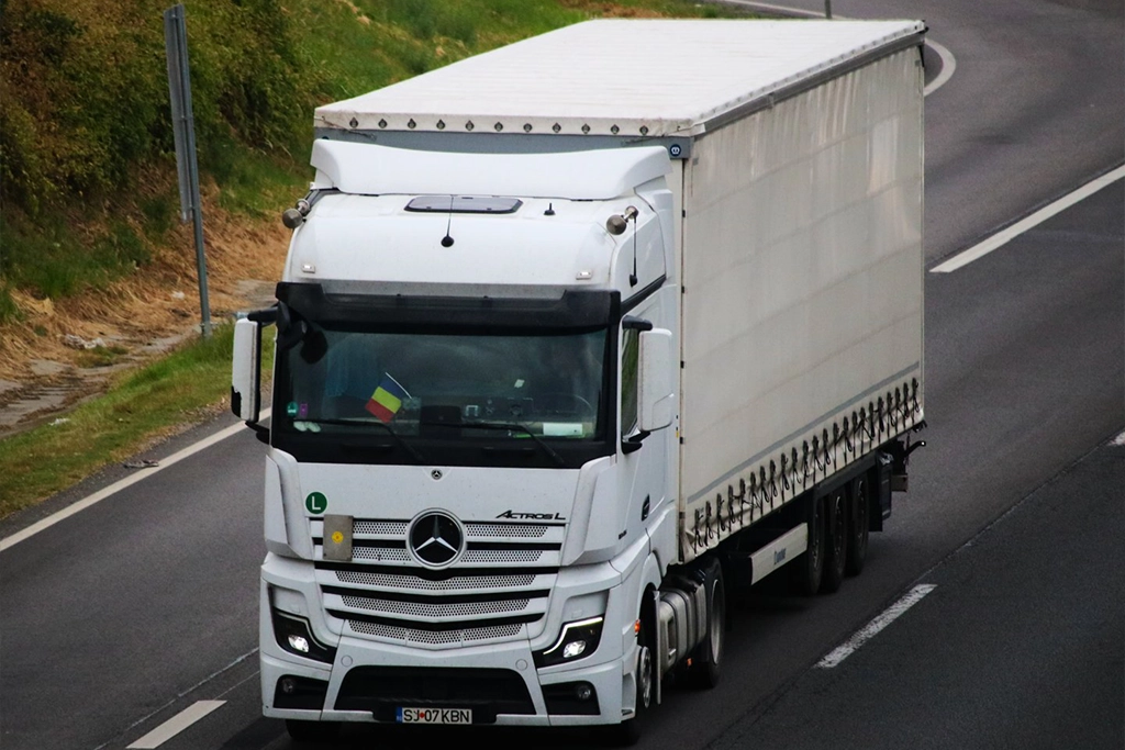 Ansamblu camion si semiremorca cu prelata din flota Express-Kbn fotografiat pe autostrada in mers